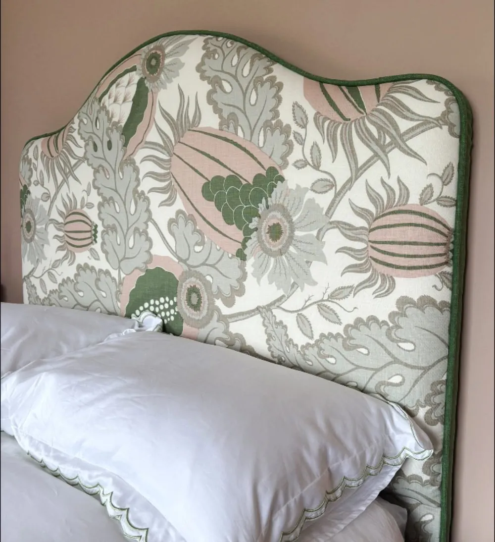 The sage botanical headboard seen from an angle, showing the shaped crown