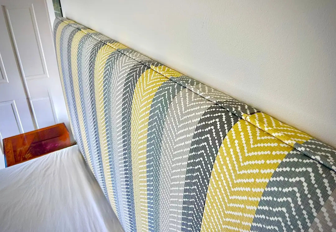 A low headboard in a mustard and grey chevron weave