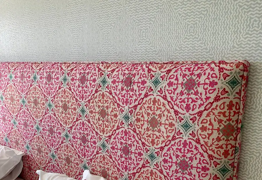 A wall-to-wall headboard in a pink and teal diamond-medallion block print