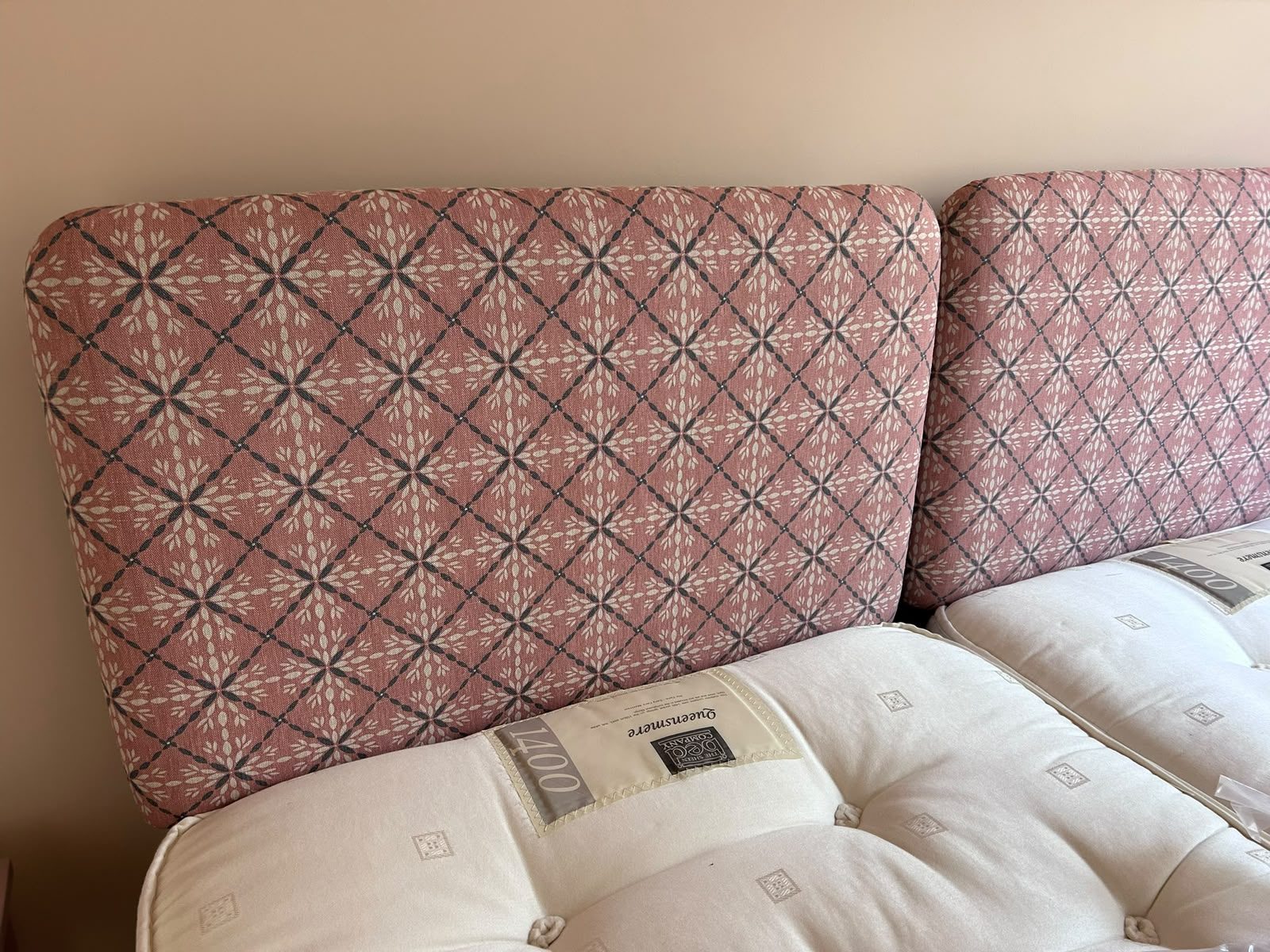 A headboard in a pink diamond-lattice weave above crisp white bedding