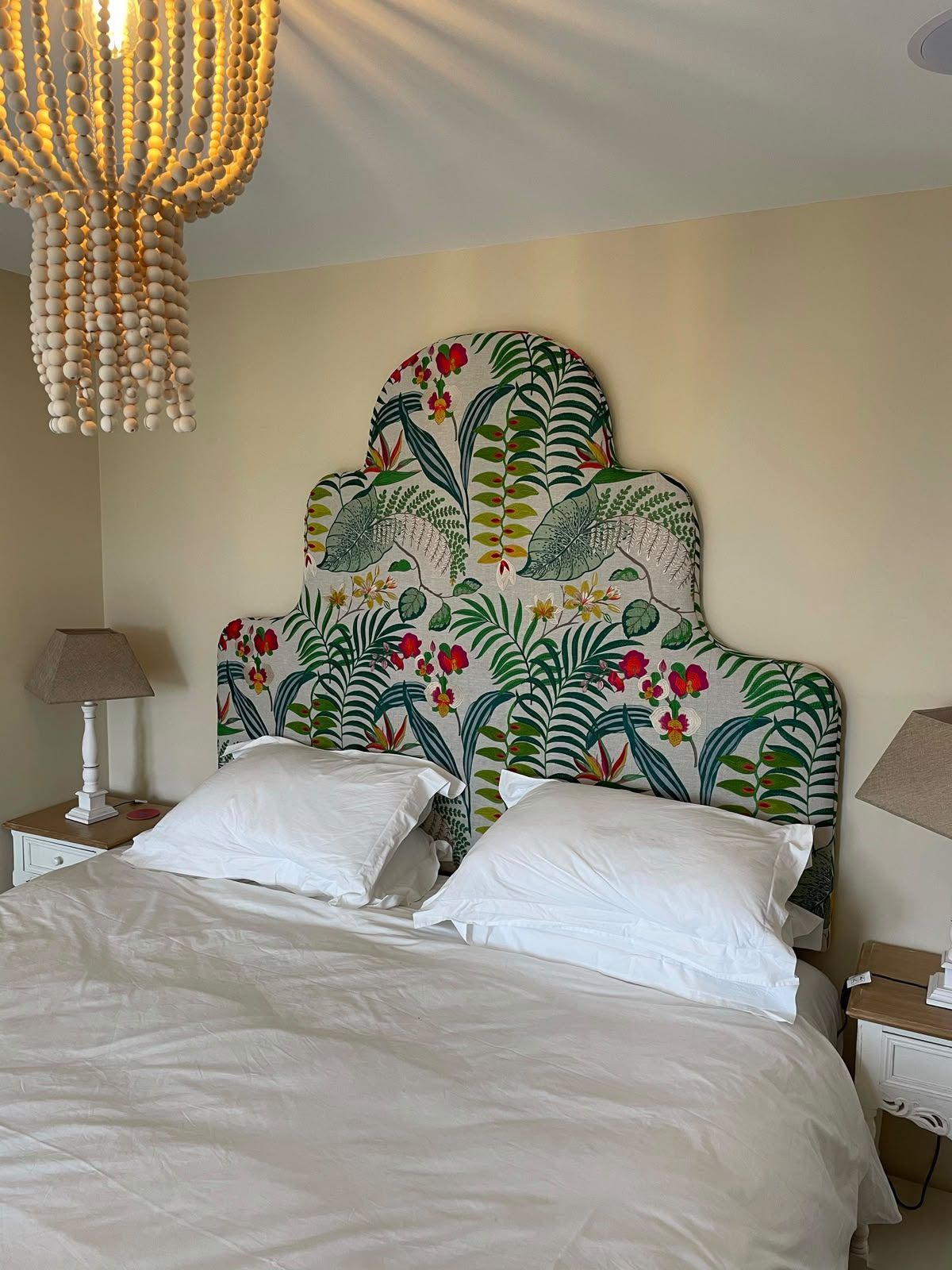 A finished bespoke headboard in a tropical botanical print, dressed for the bedroom